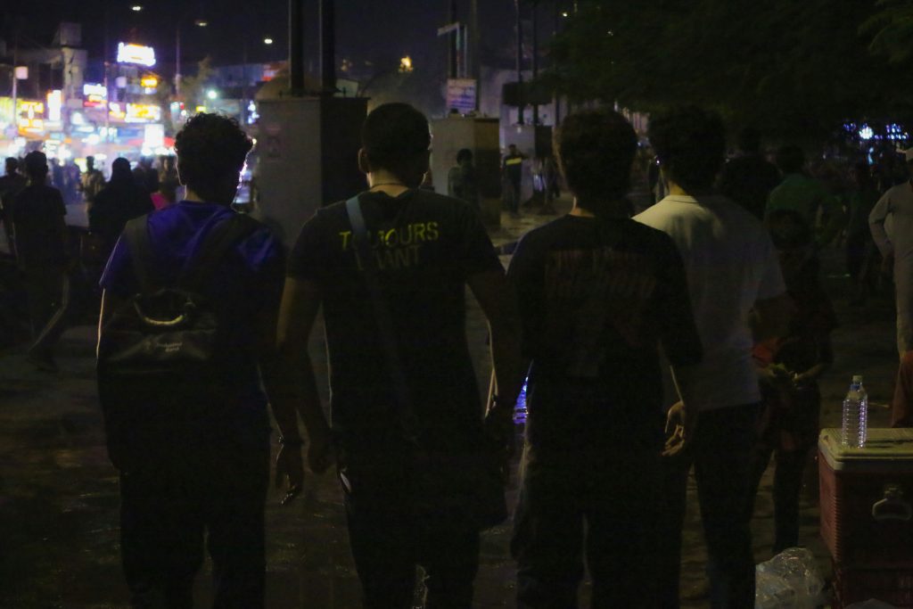 Sekelompok orang berjalan di jalan kota dengan cahaya malam